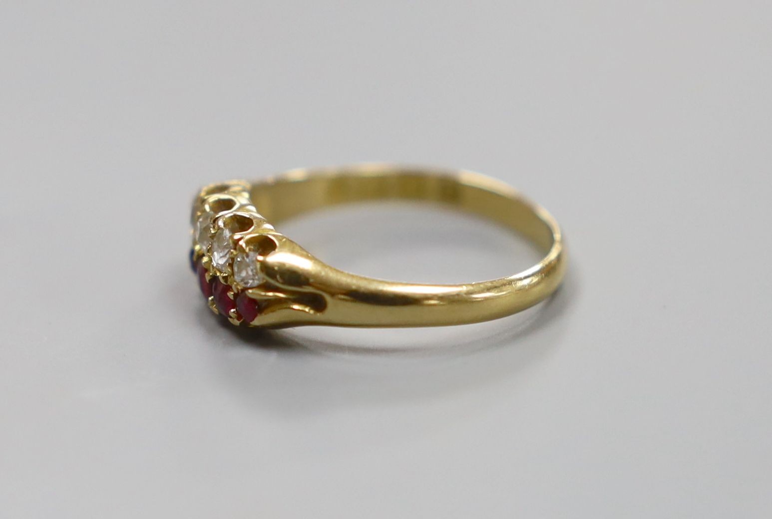 A late Victorian 18ct gold, graduated five stone ruby and five stone diamond set twin row ring, size O, gross 3 grams.